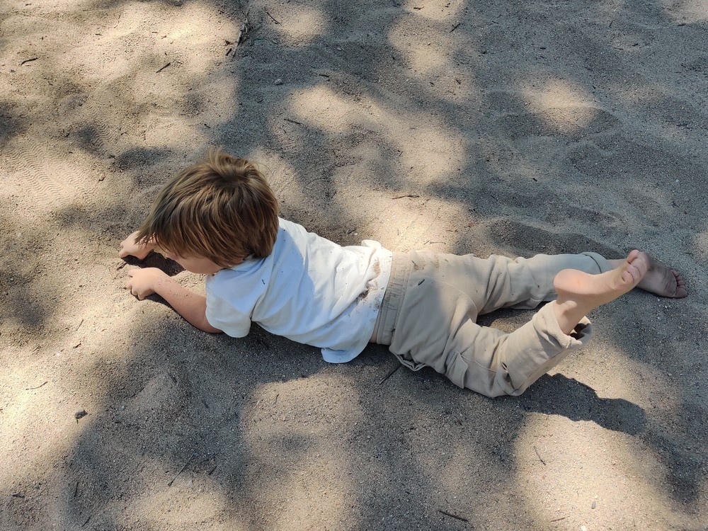Damon lying on his front on the sand.