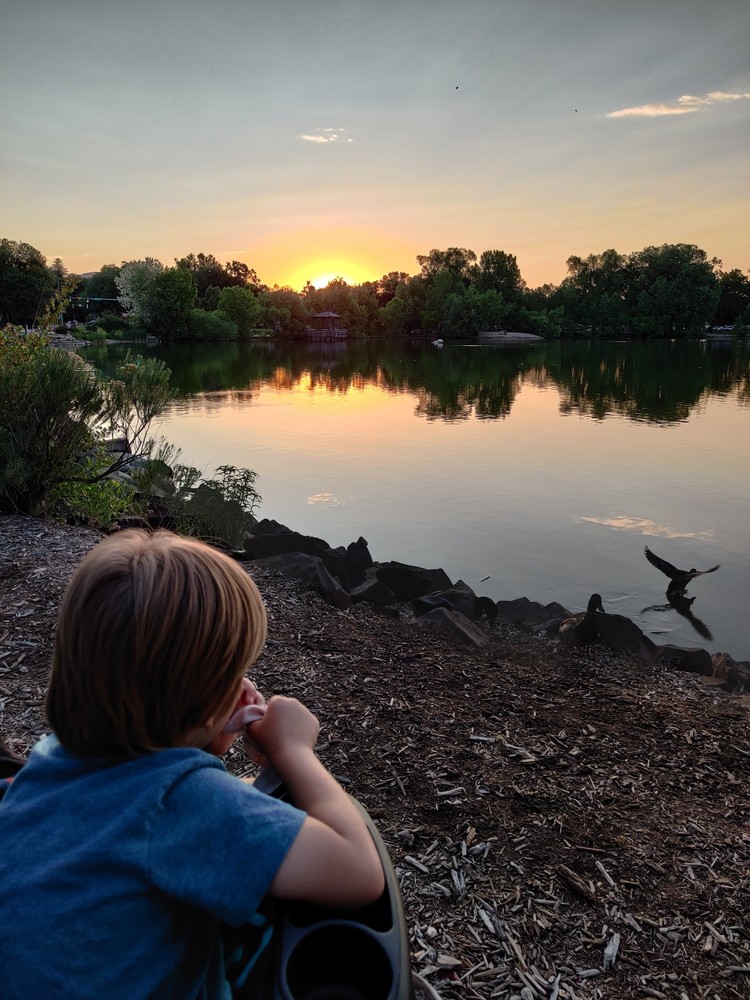 Damon watching the sun set by a lake.